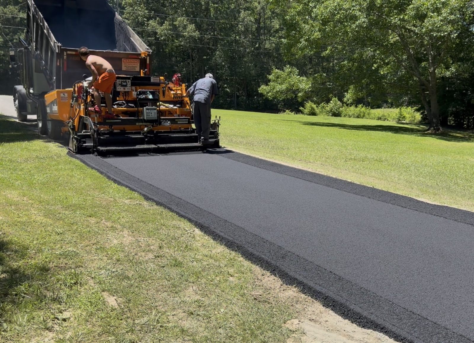 Triple R crew laying fresh hot-mix asphalt with a paver on a new driveway in Cartersville, GA
