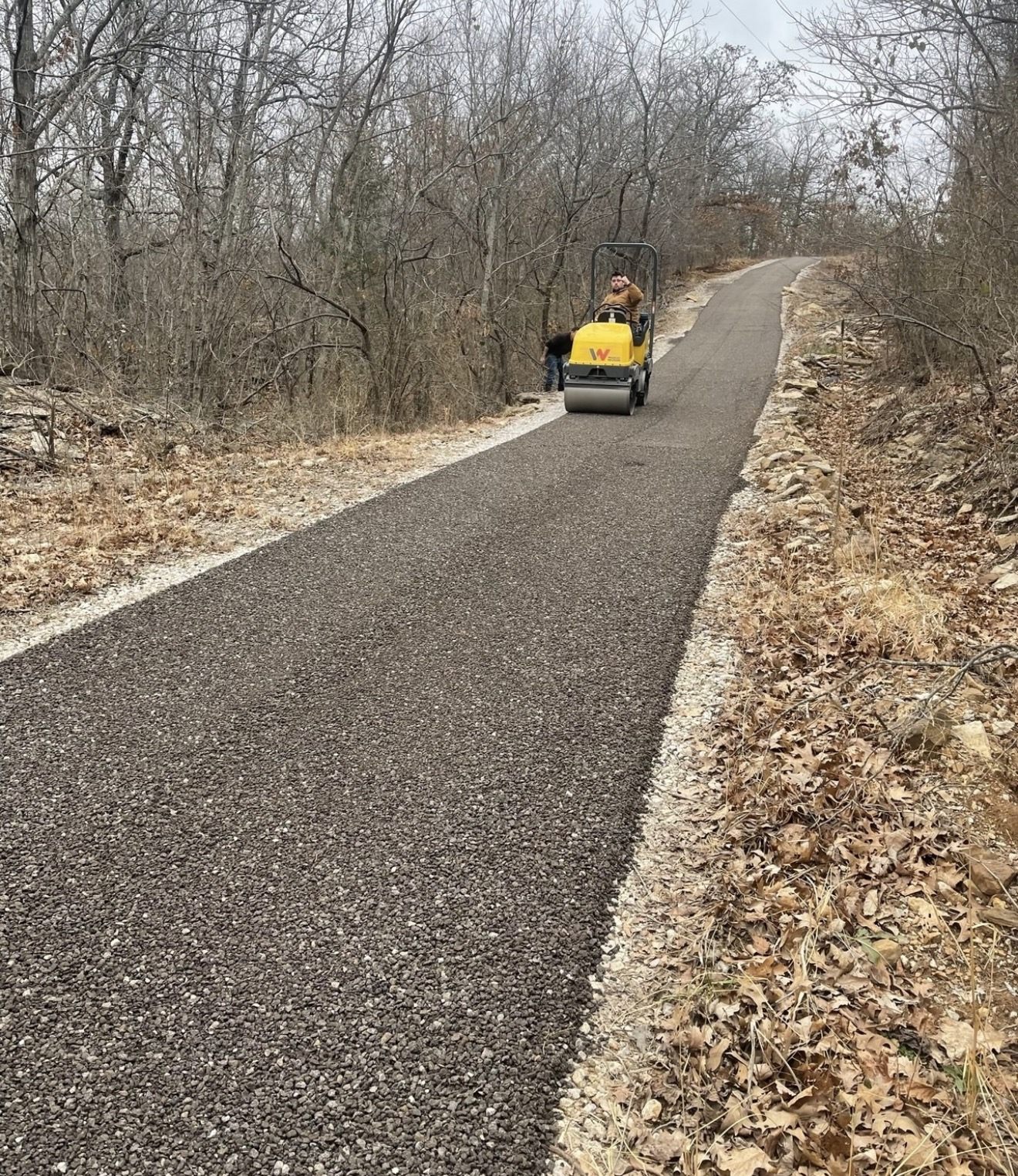 Ride-on roller compacting a new asphalt path to full density