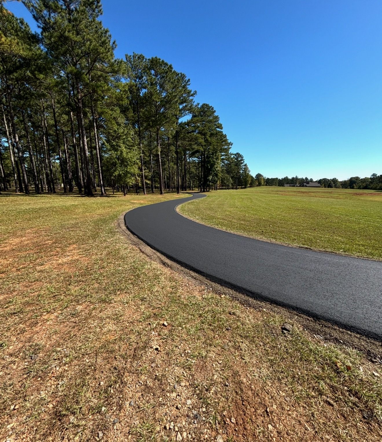 Finished asphalt driveway curving through a tree-lined property near Atlanta, GA